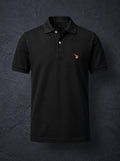 The St John Parker polo in black piqué, the embroidered bird at the left chest.