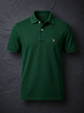 The St John Parker polo in bottle green piqué, the embroidered bird at the left chest.