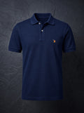 The St John Parker polo in navy piqué, the embroidered bird at the left chest.
